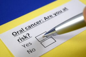 Close-up of a survey form on yellow and blue paper, asking, 'Oral cancer: Are you at risk?'' with options 'Yes' and 'No.' A pen points at the options.